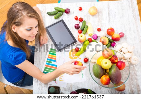 A young adult woman informing herself with a tablet PC about nutritional values of fruits and vegetables.