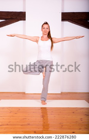 A young Woman practicing Yoga in a large attic Studio.