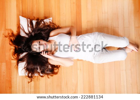 A young hispanic woman lying on the floor with a phone.