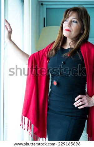 A melancholic beautiful mature woman looking out of the window.