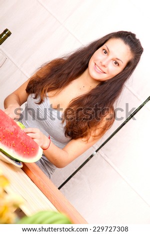 A young adult woman cutting fruits in the kitchen.