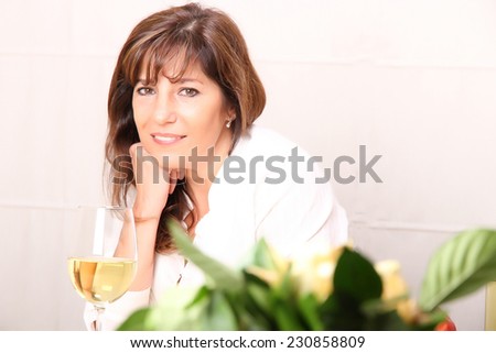 A beautiful mature woman with a glass of white wine.