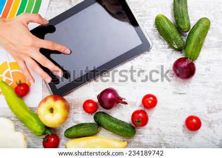 Close-up of a young adult woman informing herself with a tablet PC about nutritional values of fruits and vegetables.