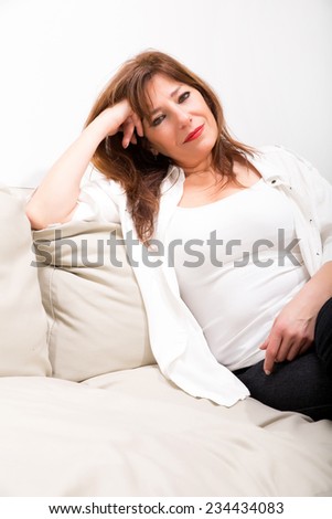 A cheerful mature woman sitting on the sofa at home.