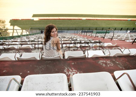 A vintage style emotional girl sitting in a sports stadium.
