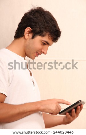 A young, latin man playing with a Tablet PC, face in focus