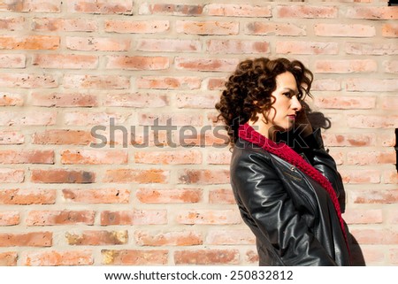 Content woman standing at brick wall on the street.