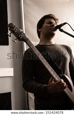 A Rock singer playing bass in the rehearsal Studio.
