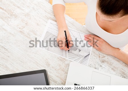 A young adult woman developing a architectural plan at home.