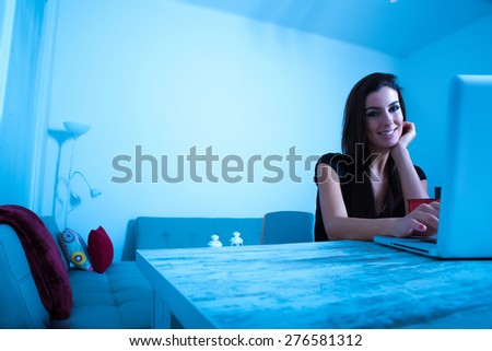 A young beautiful woman using a Laptop computer at home at night time.