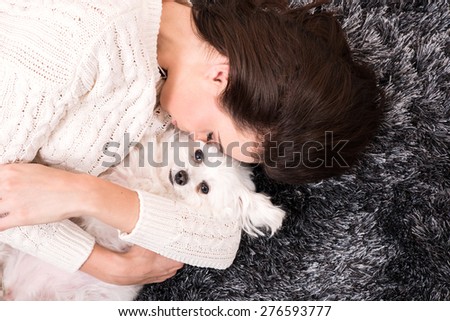 A young beautiful woman cuddling her Dog on the carpet in the living room.