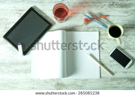 A desktop with a Tablet PC, a exercise book, a smartphone and various office supplies.