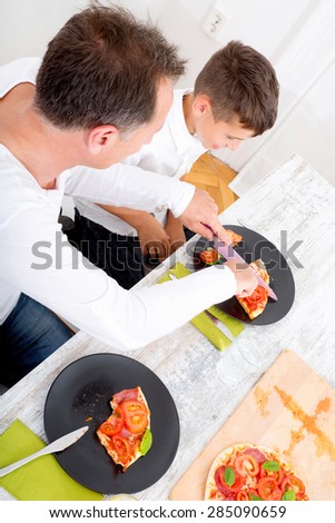 Father and son  eating Pizza for lunch or dinner.