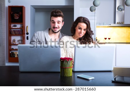 A young couple in the evening using their laptop computers at home.