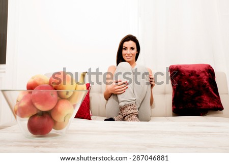 Young beautiful woman sitting on the couch wearing worn-out socks