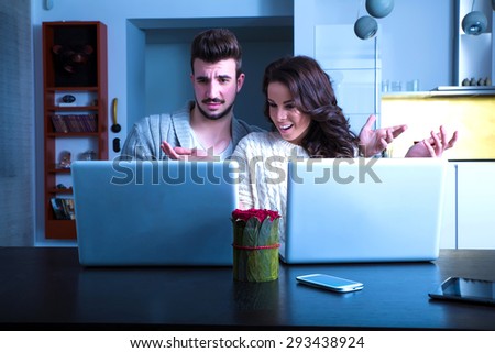 A young couple using in the evening their laptop computers at home and visiting a strange website.