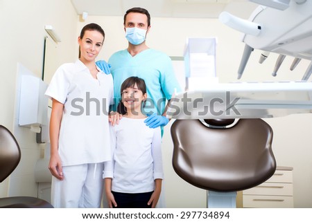 A dentist with his assistant taking care of a little girl.