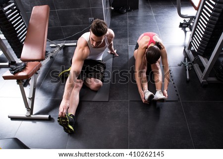 A young couple stretching in the gym