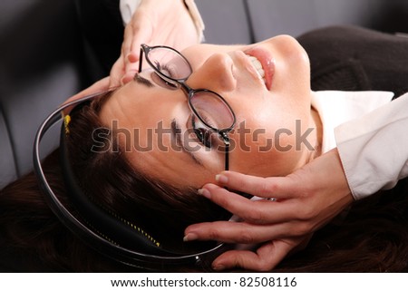 A girl listening to Music with headphones on the sofa.