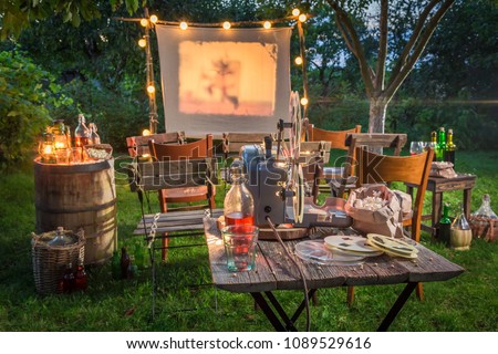 Open air cinema with retro projector in summer garden