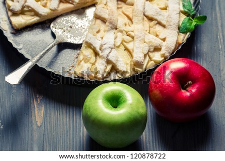 Two apples and freshly baked apple pie on old blue table