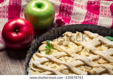 Two apples and freshly baked apple pie on tea towels