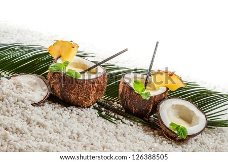 Few pinacolada drinks in coconut on white beach