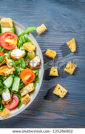 Healthy Caesar salad made of fresh vegetables on blue table
