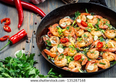 Freshly fried shrimps with herbs on old pan