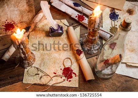 Antique table filled with old papers, red sealant and candles