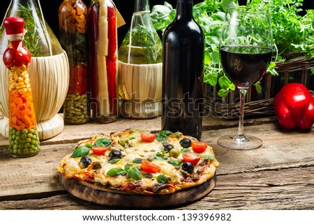 Baked pizza served with wine on the background of fresh vegetables