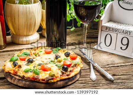 Freshly baked pizza served with wine on a calendar background