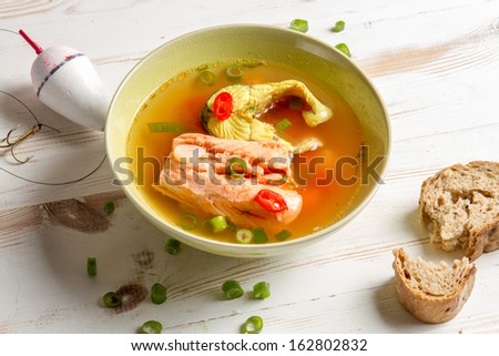 Salmon soup served with bread on old wooden table