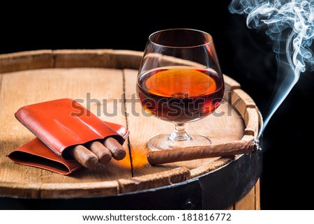 Cognac in a glass on barrel and burning cigar