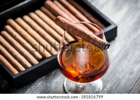 Burning cigar on glass with cognac