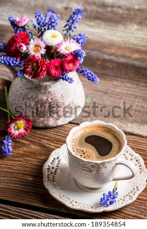 Coffee and spring flowers on old wooden table