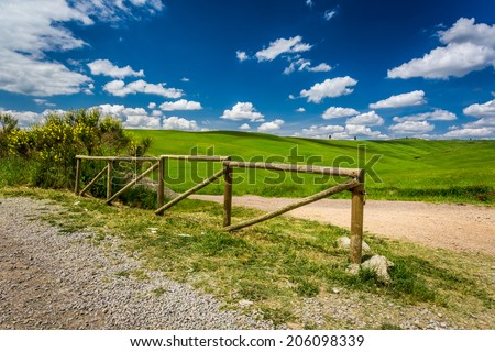 Old wooden fence, dirt road and green field