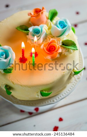 Sweet birthday cake decorated with candles and roses