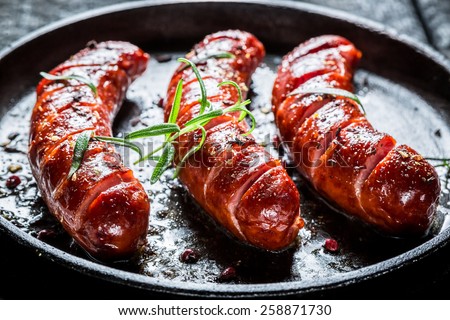 Grilled sausage with fresh rosemary on hot barbecue dish