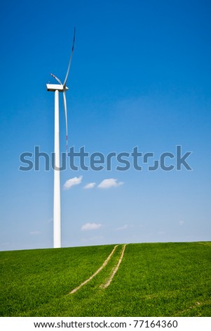 Wind Turbine with path on green field with blue sky