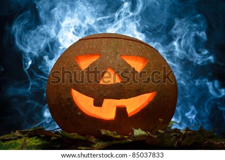 Halloween pumpkin on leafs with blue smoke