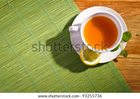 Hot tea with fresh leves and lemon on bamboo mat