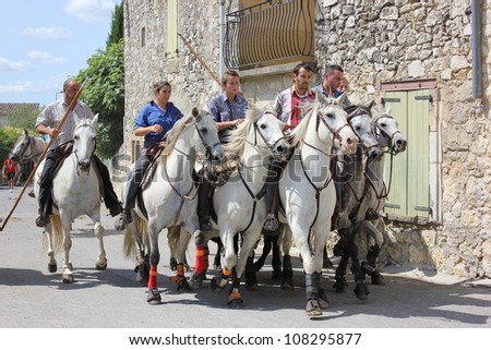 BLAUZAC, FRANCE - JUL 15: Herd of horses runs from the bulls in a street of Blauzac during village traditional summer festival on July 15, 2012 in Blauzac, Gard France. A festival called abrivado.
