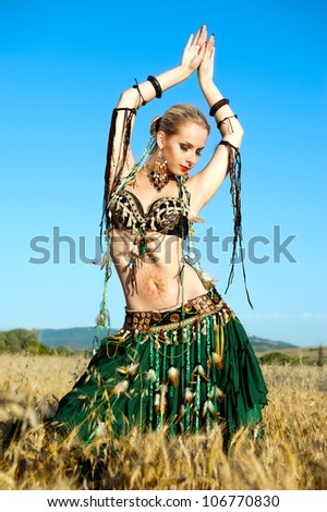 young woman dances tribal in the field of wheat