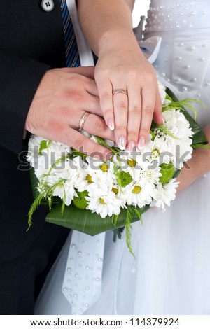 Hands with wedding rings and flower bouquet