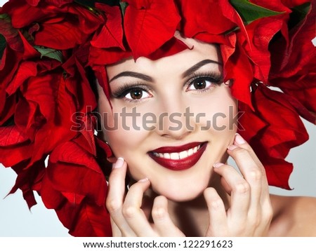 Portrait of beautiful woman with stylish makeup and red xmas flowers in her hair. Xmas style