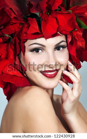 Beautiful woman with stylish makeup and red xmas flowers in her hair. Xmas style