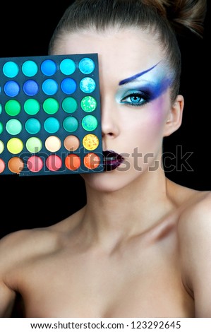 Beautiful woman with a bright makeup holding the box with the shadows to his eyes. Make-up artist