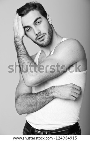 Fashion portrait of the young beautiful man in white t-shirt, series photo. Black-and-white photo.
