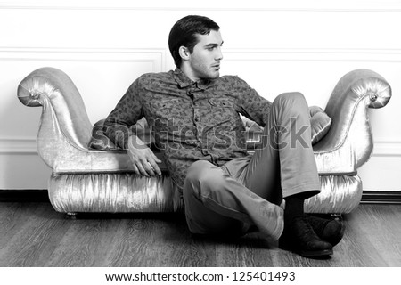 handsome young male model posing on sofa. Black-and-white photo.